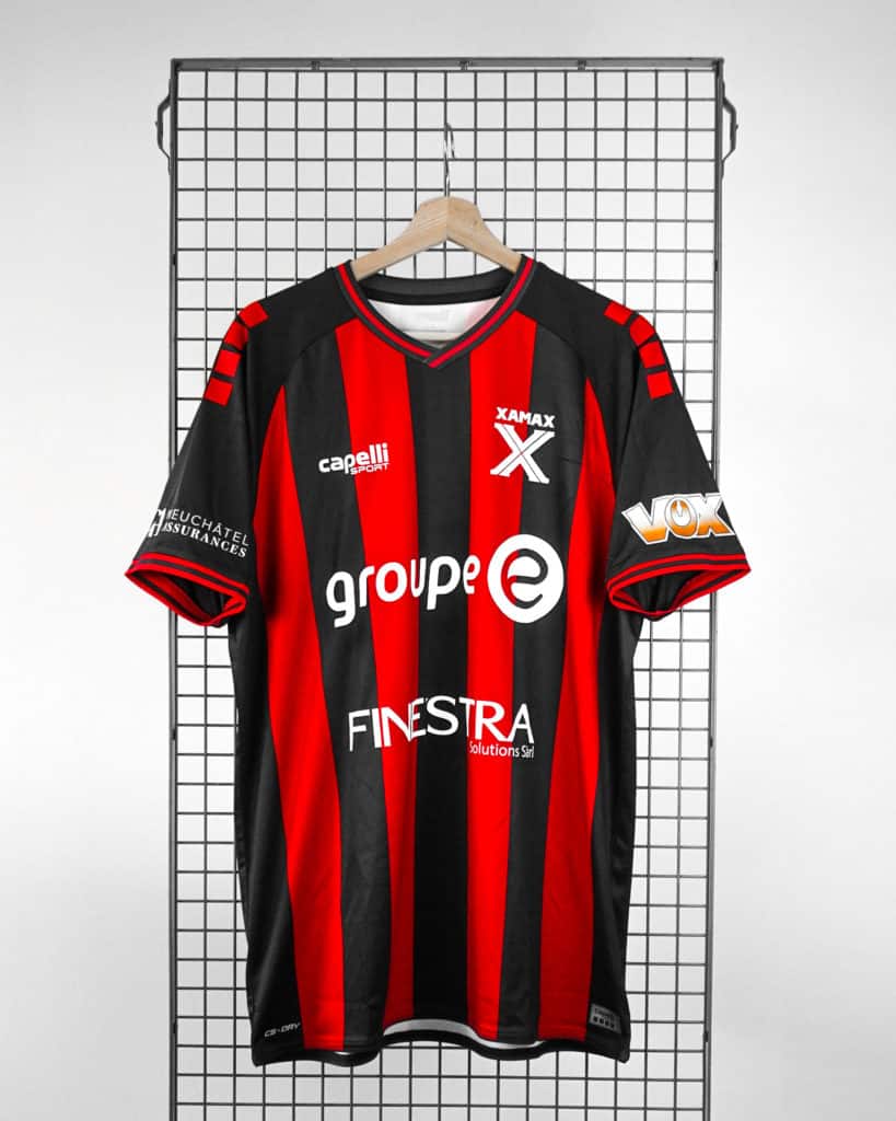 Veste de football avec rayures rouges et noires, logos de sponsoring, adaptable à la promotion sportive, parfaite pour les clubs locaux ou les amateurs de sport dans la région de Neuchâtel.