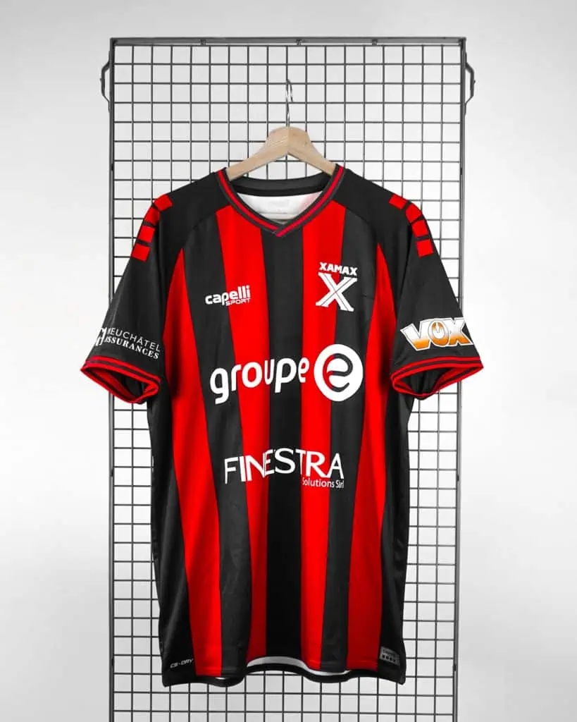 Veste de football avec rayures rouges et noires, logos de sponsoring, adaptable à la promotion sportive, parfaite pour les clubs locaux ou les amateurs de sport dans la région de Neuchâtel.