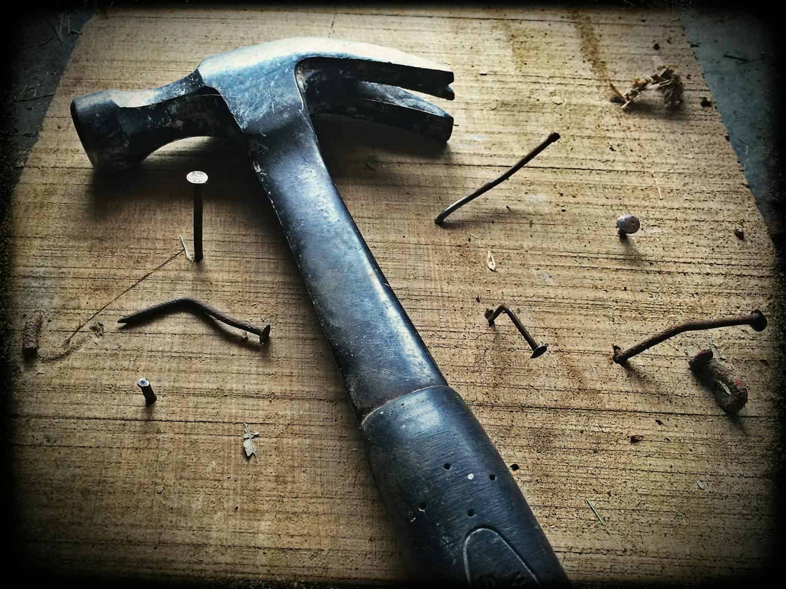 Clou et marteau rouillés sur une planche en bois, symboles de réparation ou de clouage. Outil de bricolage utilisé pour fixer ou assembler divers matériaux, souvent en bois. Concept de construction ou de travaux manuels.