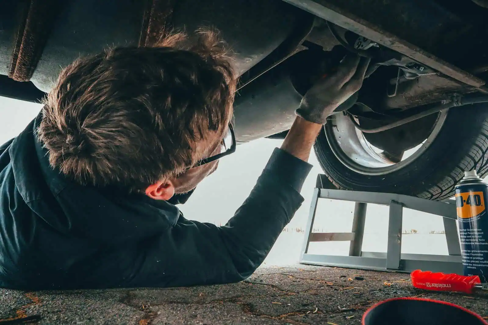 Remontage de voiture, technicien automobile inspectant le dessous d’un véhicule pour assurance, réparation ou entretien. Service professionnel d'assurance et de réparation automobile à Neuchâtel.