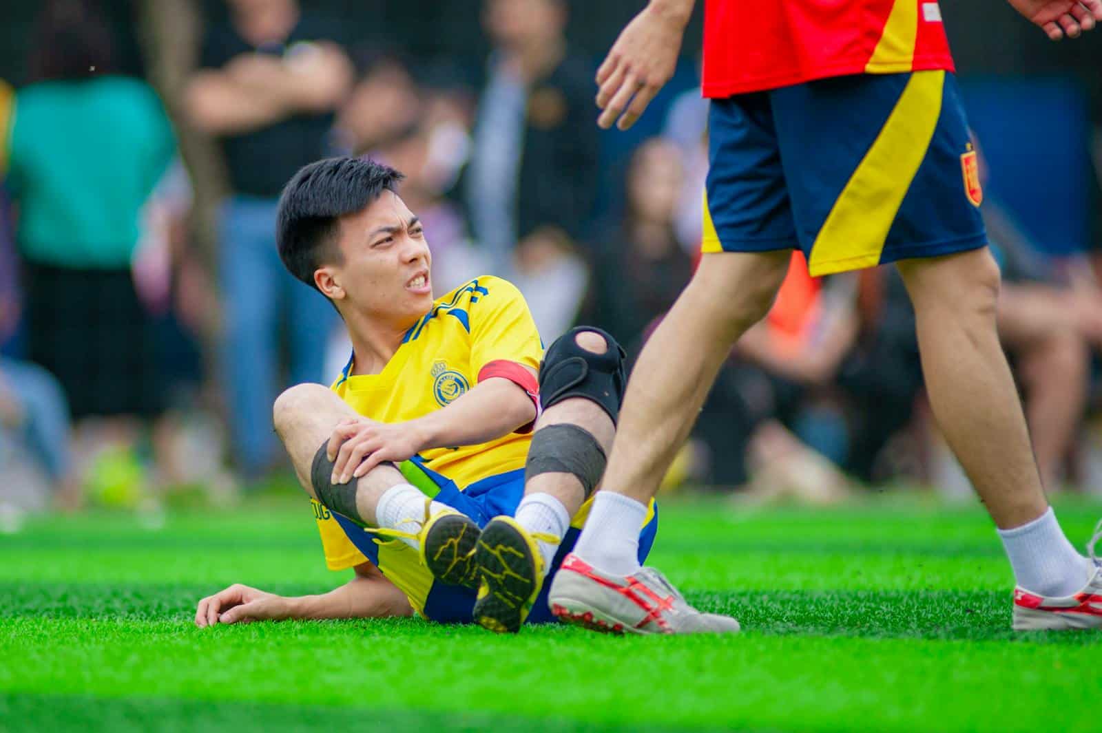 Tapis d'herbe lors d'un match de football, joueur blessé sur le terrain, assistance médicale, assurance sport, sécurité pour sportifs.