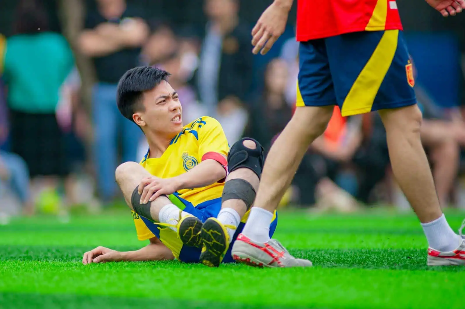 Tapis d'herbe lors d'un match de football, joueur blessé sur le terrain, assistance médicale, assurance sport, sécurité pour sportifs.