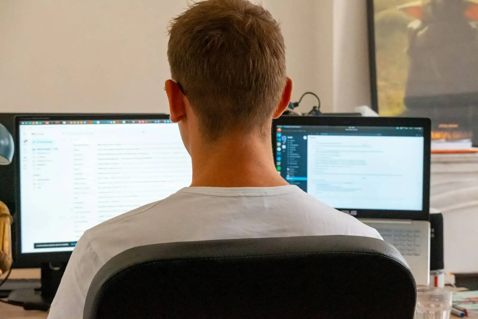 Travailleur utilisant deux écrans d'ordinateur pour assurer des tâches administratives ou professionnelles, illustrant la productivité et la gestion digitale.