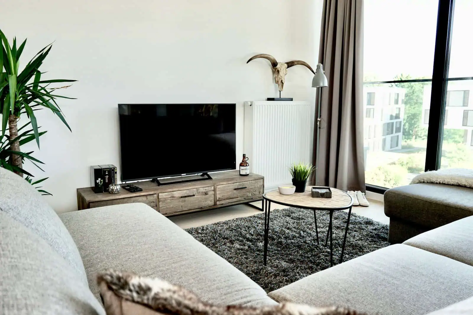 Modern living room with large windows, cozy sofas, and contemporary decor in a stylish apartment.