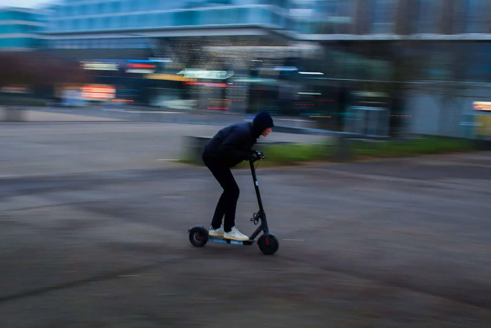Vélos en assurance Neuchâtel, jeune homme roulant en trottinette électrique en ville, sécurité et mobilité urbaine, assurance pour véhicules électriques, dynamique et moderne.