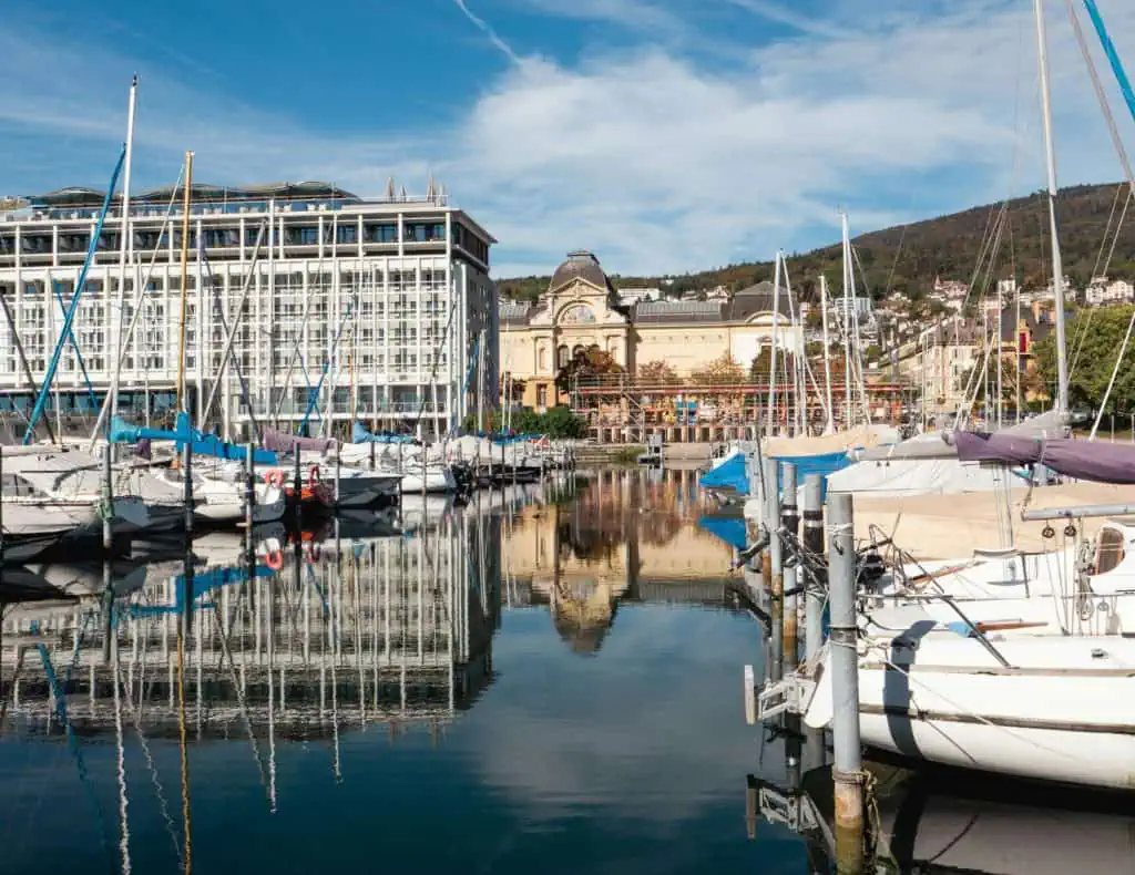 Vieux port de Neuchâtel avec yachts et bâtiments historiques, vue pittoresque sur le lac, assurance nautique et protection pour plaisanciers à Neuchâtel.