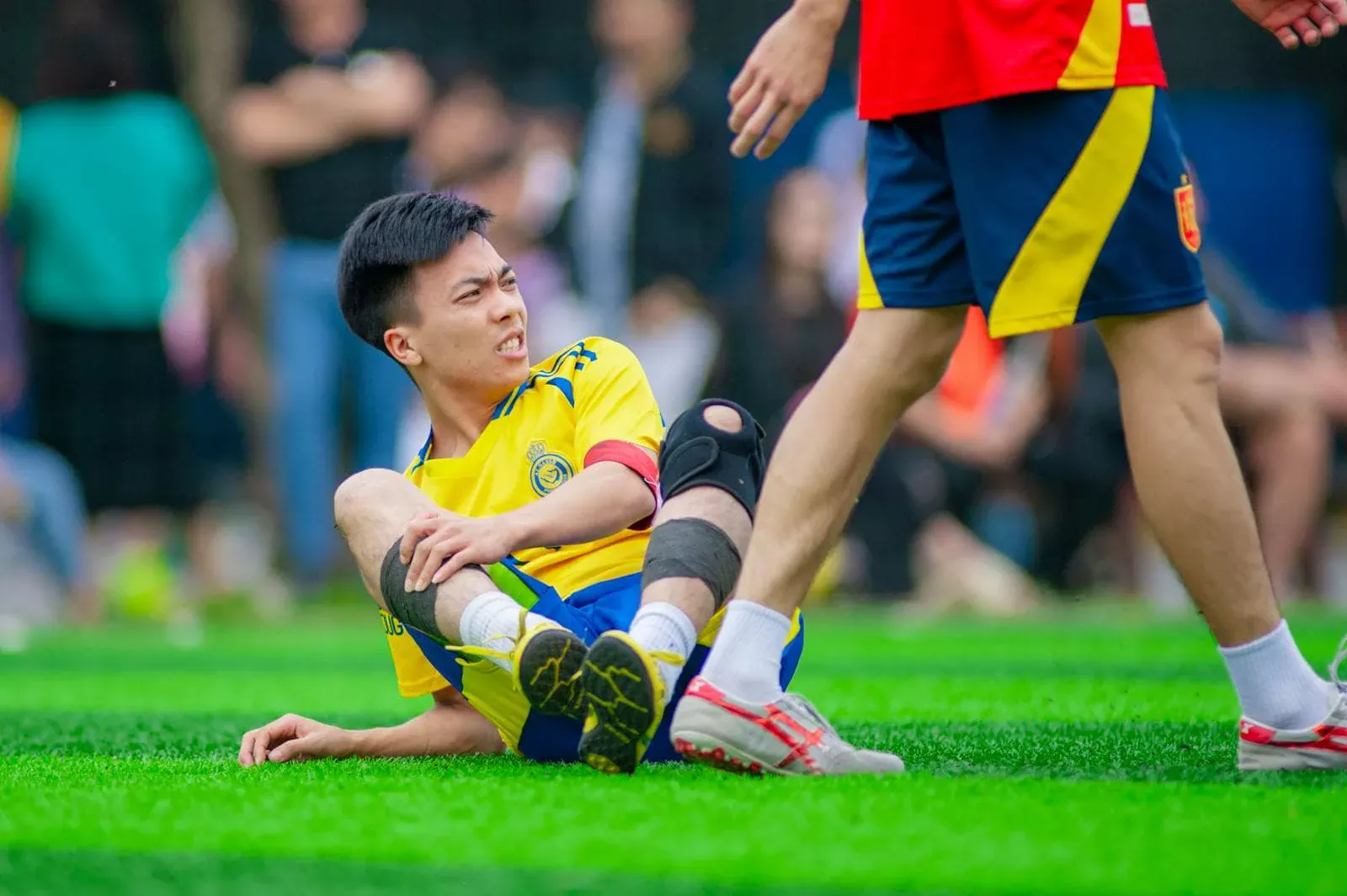 Tapis d'herbe lors d'un match de football, joueur blessé sur le terrain, assistance médicale, assurance sport, sécurité pour sportifs.