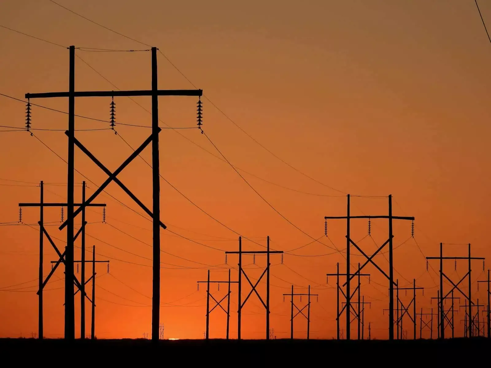 Lignes électriques au coucher du soleil illustrant sécurité et fiabilité dans les solutions d'assurance.