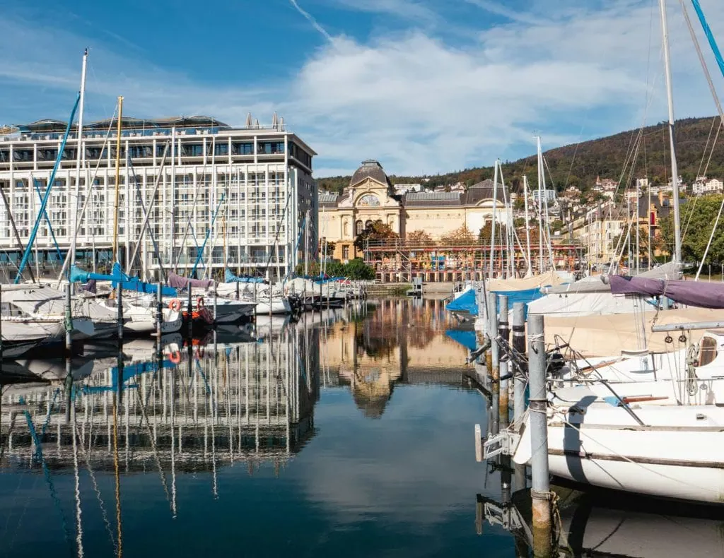 Vieux port de Neuchâtel avec yachts et bâtiments historiques, vue pittoresque sur le lac, assurance nautique et protection pour plaisanciers à Neuchâtel.